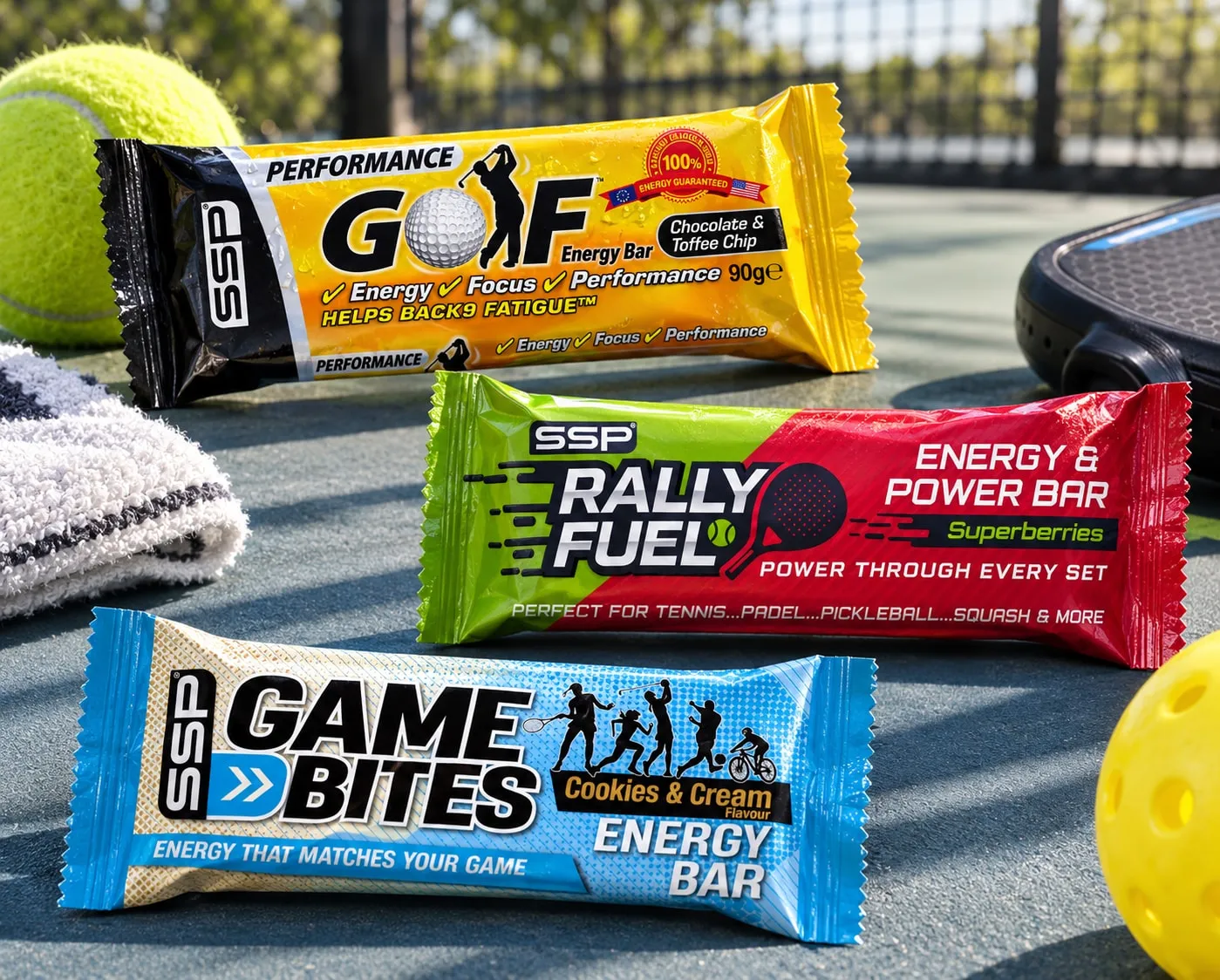 SSP Golf, Rally Fuel and Game Bites energy bars on a tennis court with balls and a padel racket.
